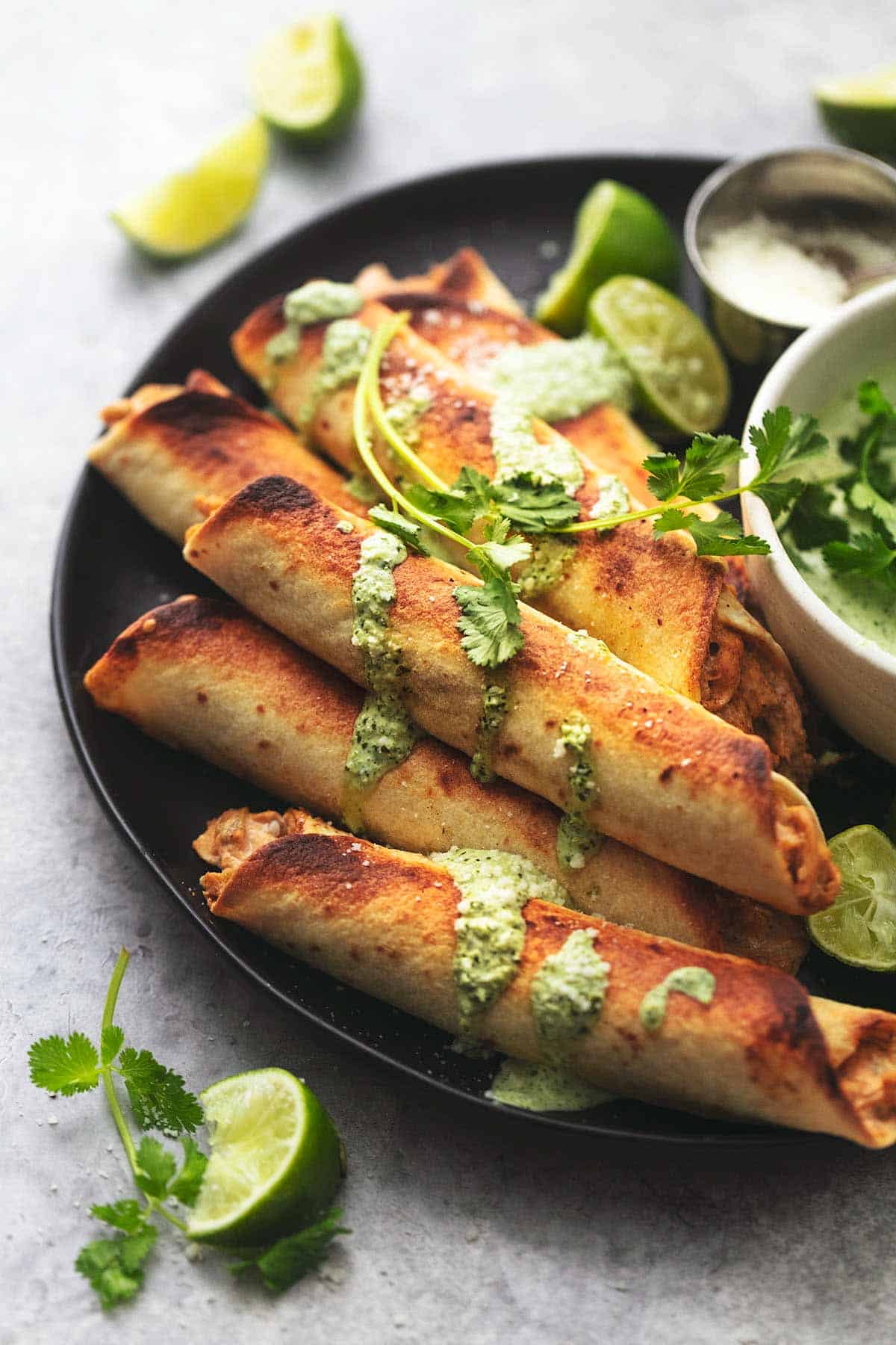 instant pot chicken taquitos on a plate with lime slices and sauce.