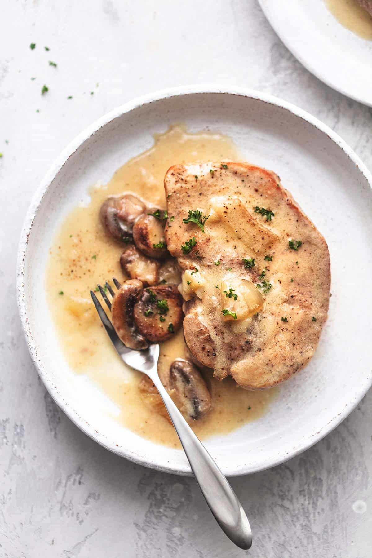 top view of a instant pot pork chop with gravy with a fork on a plate.