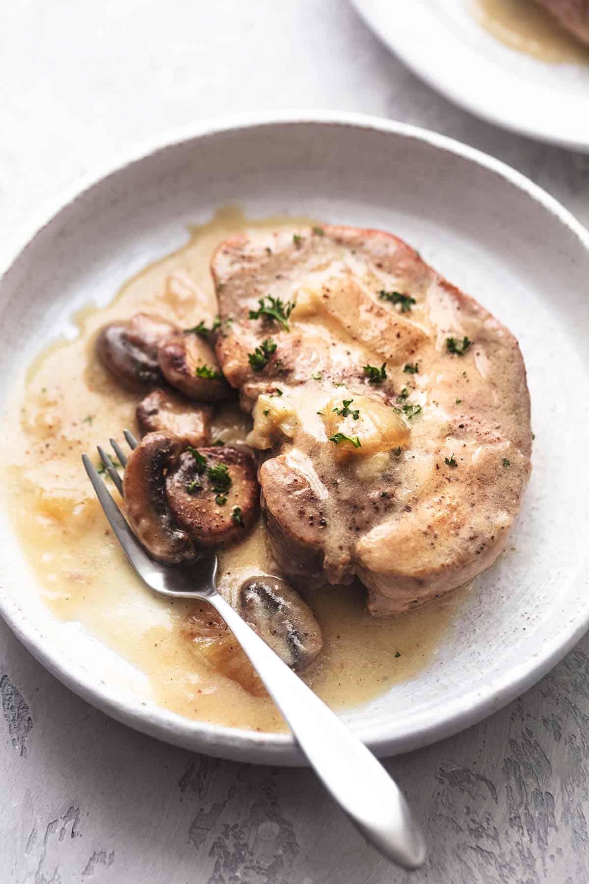 up close pork chop with gravy on white plate