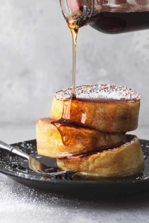 up close syrup pouring on stacked japanese pancakes