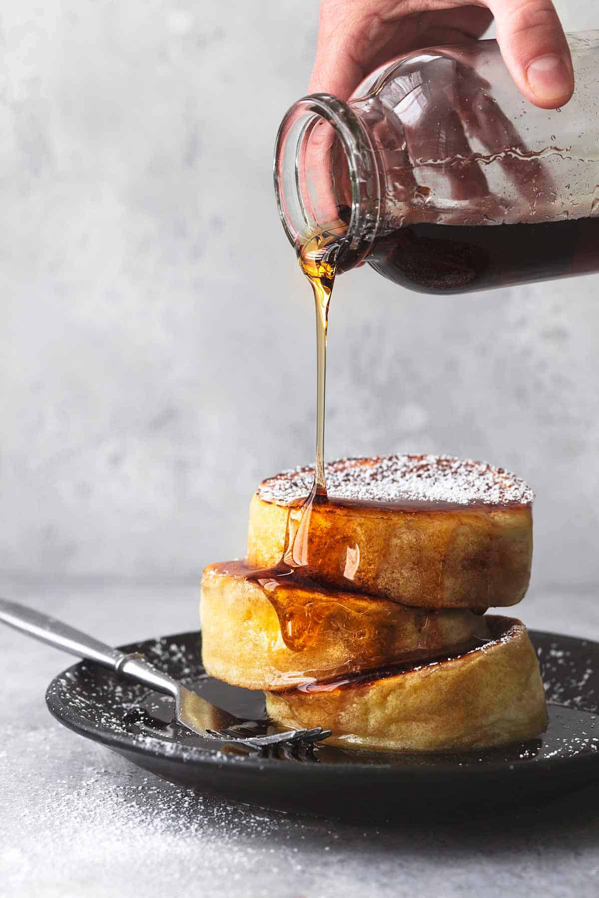 close up of a stack of Japanese soufflé pancakes with syrup being poured on top.