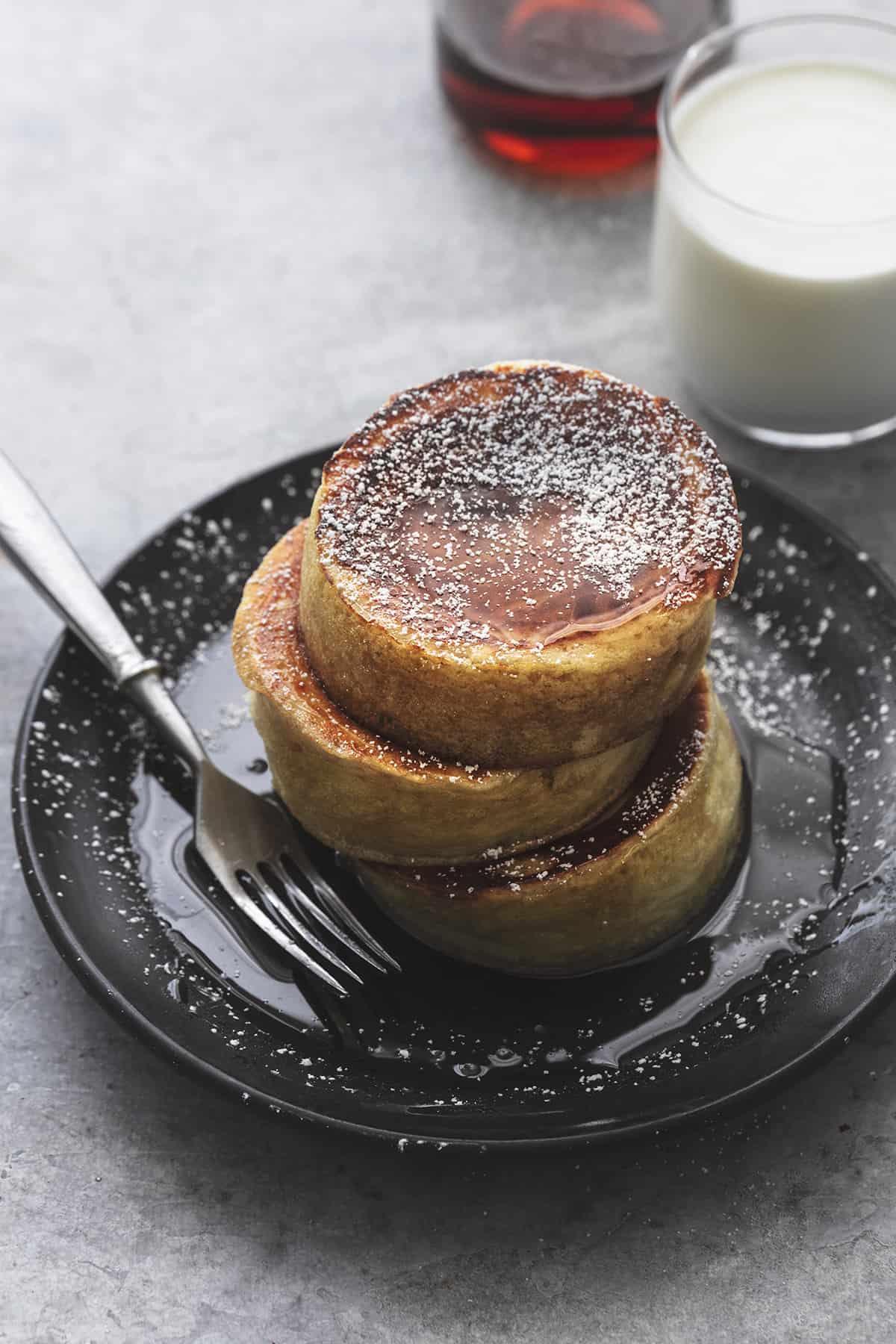 stacked japanese souffle pancakes on plate with fork and glass of milk