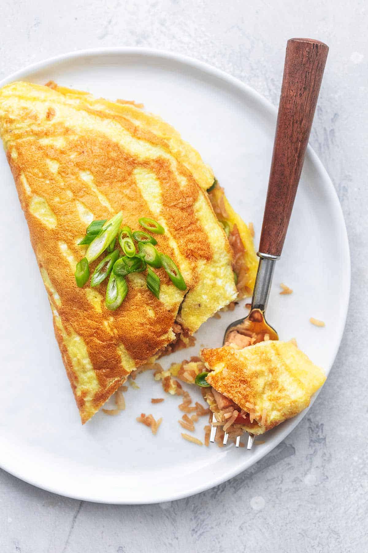 top view of a Japanese rice omelet with a bite on a fork on the side on a plate.