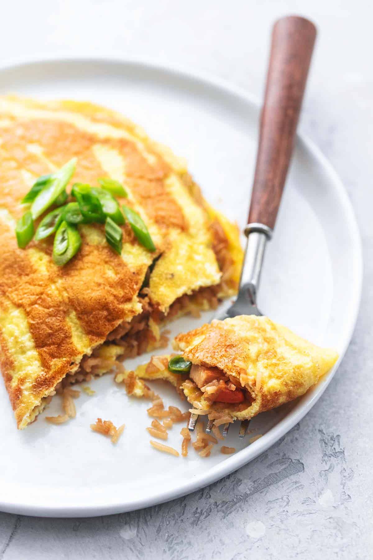 close up of a bite of a Japanese rice omelet with the rest of the omelet on the side on a plate.