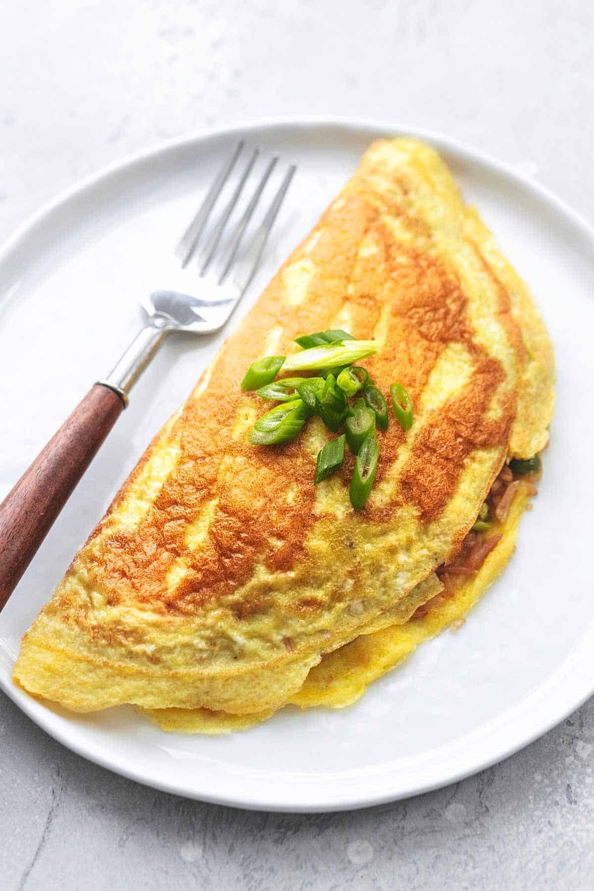 close up of a Japanese rice omelet with a fork on a plate.