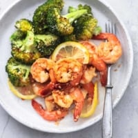 overhead shrimp and broccoli with lemon slices on white plate with fork