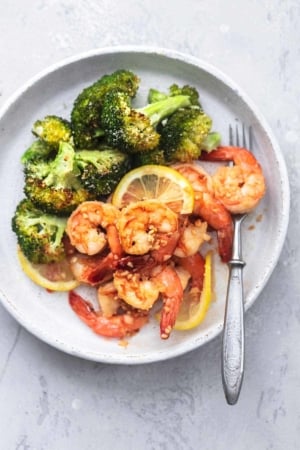 overhead shrimp and broccoli with lemon slices on white plate with fork