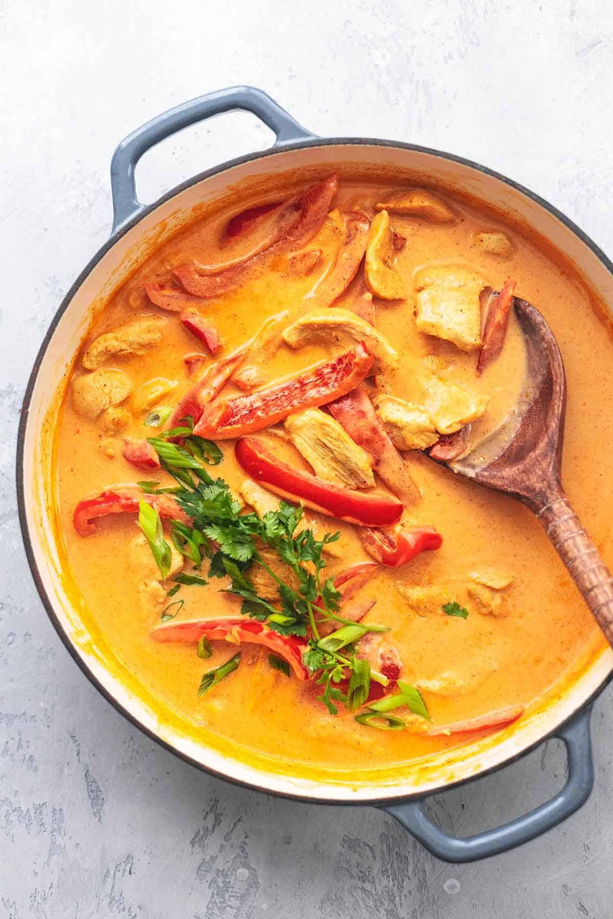 top view of Thai chicken curry with coconut milk with a serving spoon in a skillet.