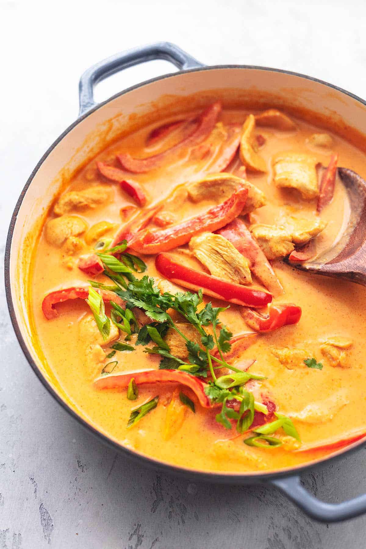 Thai chicken curry with coconut milk with a serving spoon in a skillet.