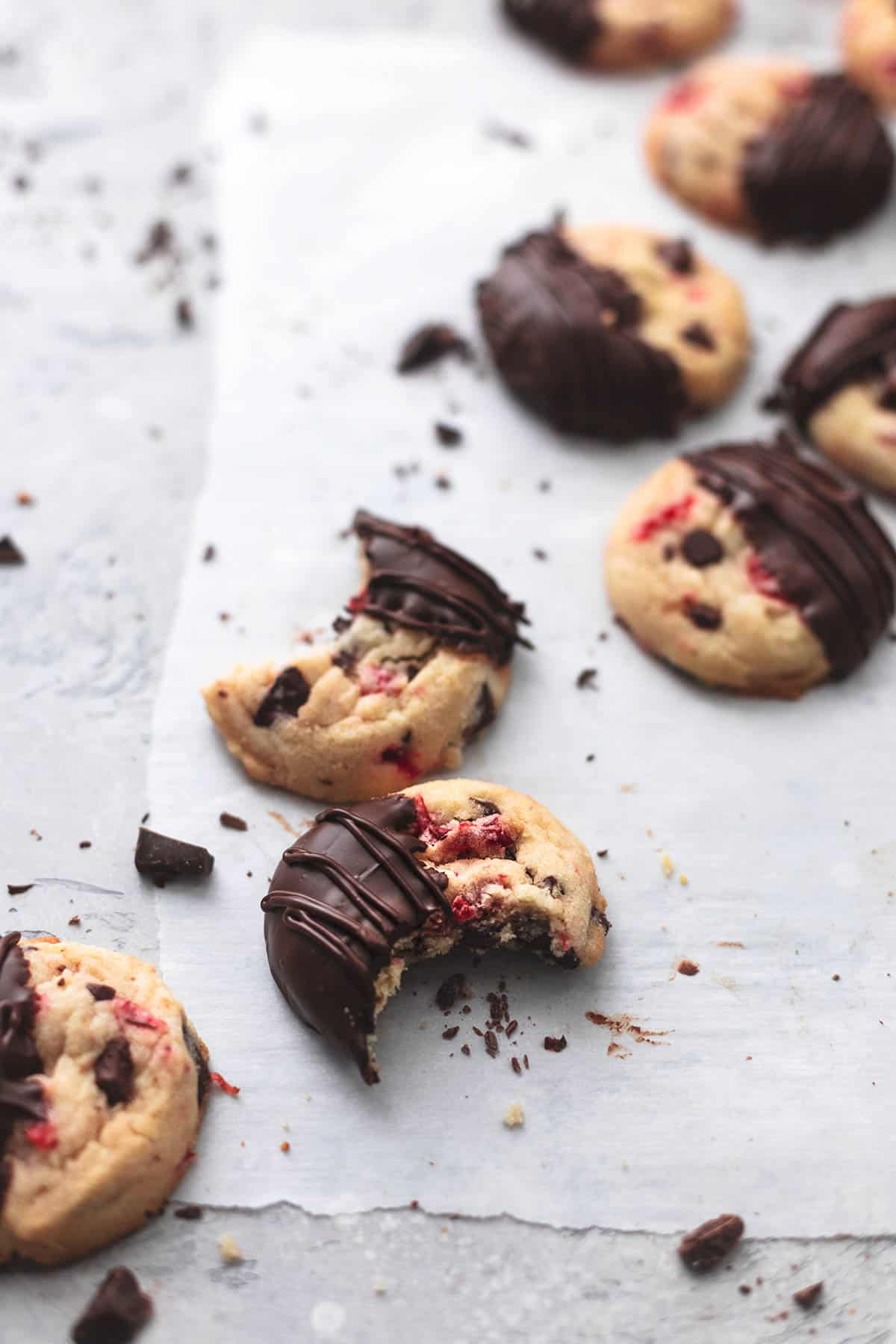 cherry Garcia cookies on parchment paper with some having bites taken out of them.