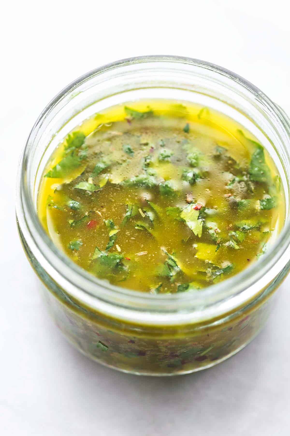 cilantro lime marinade in a clear jar on a marble table.