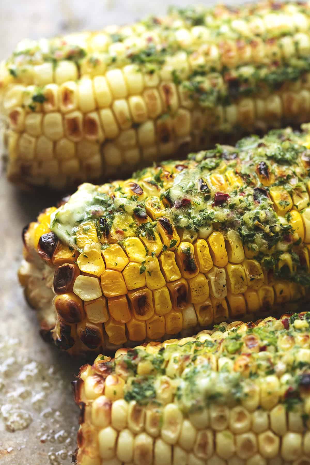 close up of grilled corn on the cob with chimichurri butter.
