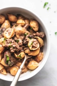 overhead view of half of a white bowl with fork and ground beef stroganoff