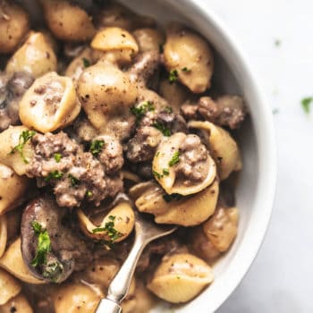 overhead view of half of a white bowl with fork and ground beef stroganoff