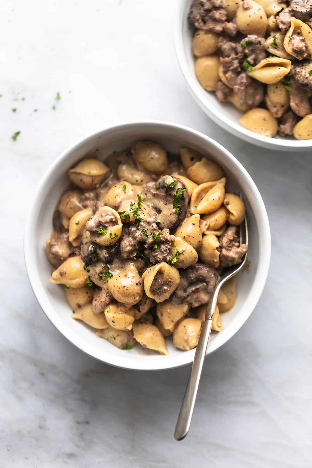 overhead view of one whole and one partial bowl of pasta with beef and parsley