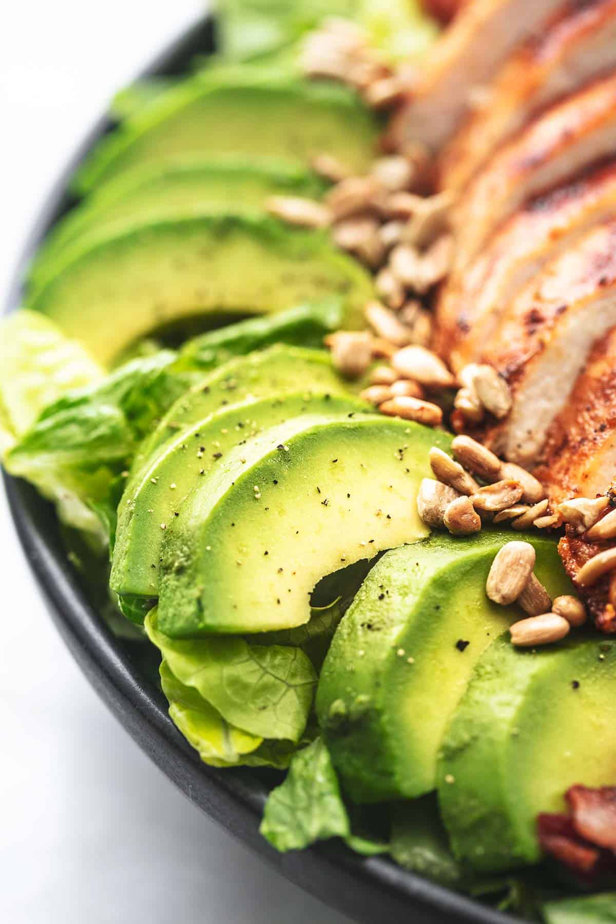 close up of sliced avocado and sesame seeds from chicken cobb salad.