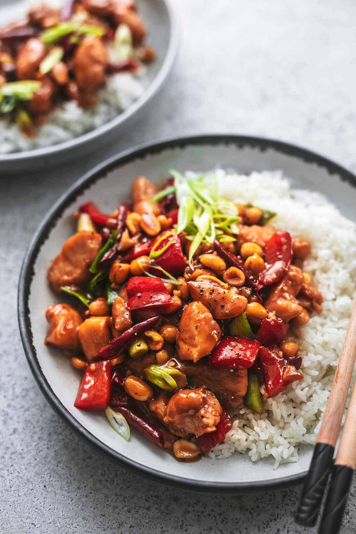 kung pao chicken with white rice in a bowl with chopsticks.