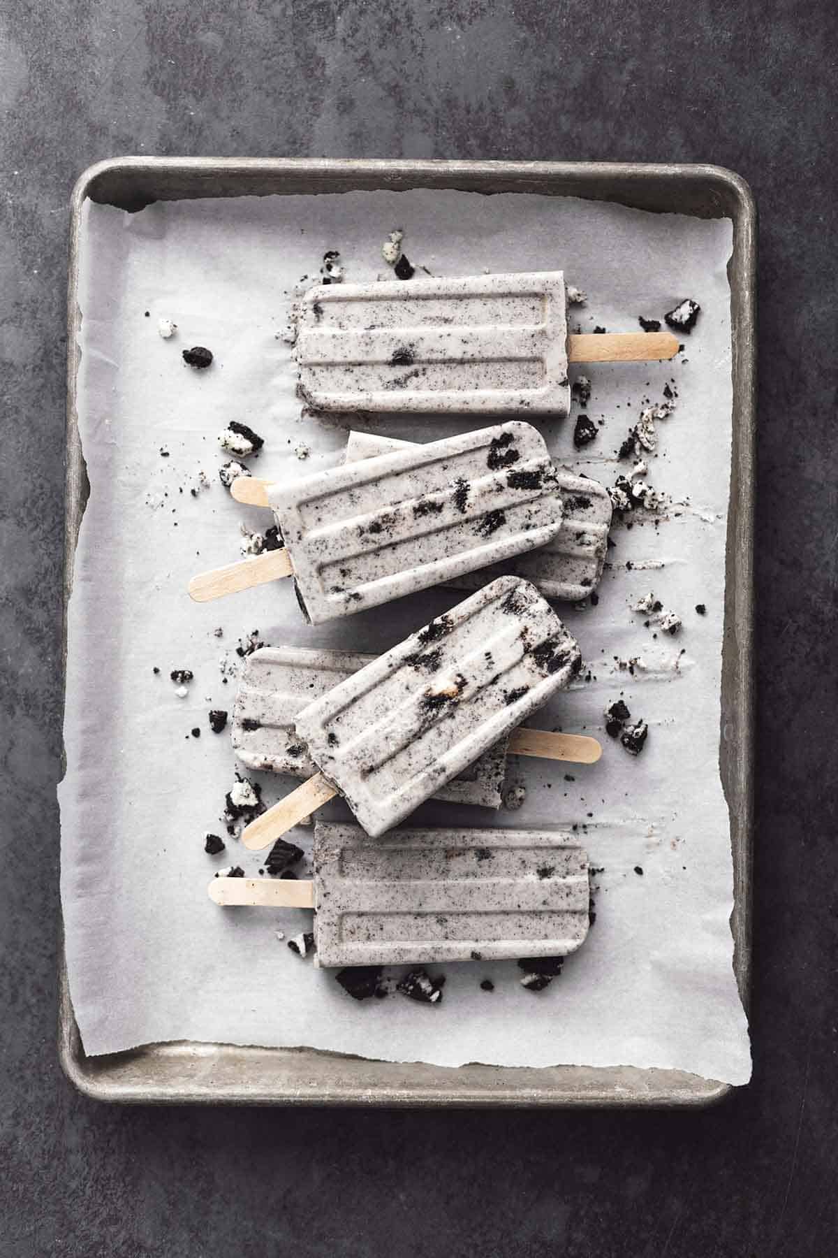 pile of oreo popsicles on a parchment lined baking sheet