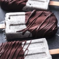 chocolate covered oreo popsicles laying on black surface