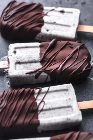 chocolate covered oreo popsicles laying on black surface
