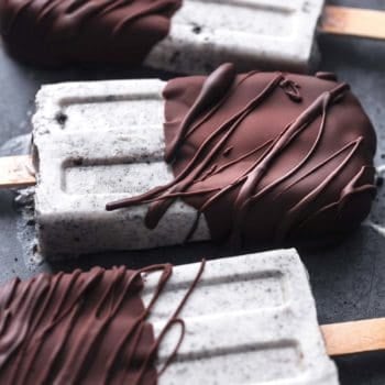 chocolate covered oreo popsicles laying on black surface