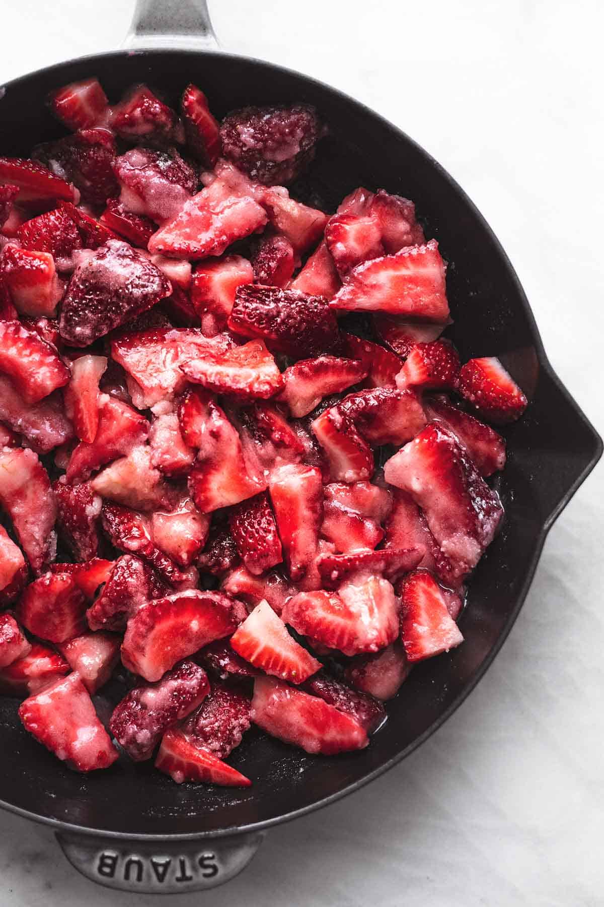 top view of sugared sliced strawberries in a cast iron skillet.