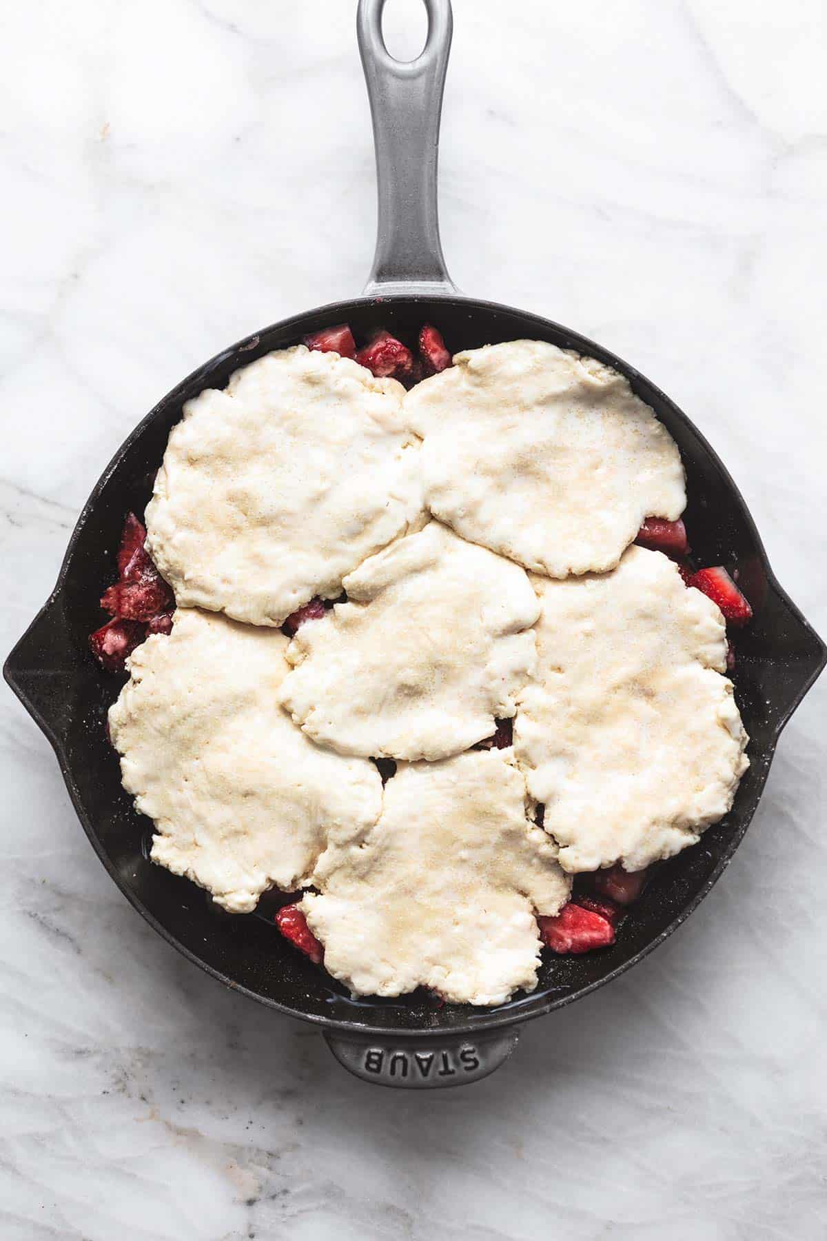 top view of unbaked strawberry cobbler in a cast iron skillet.