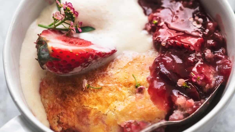 up close view of strawberry cobbler with ice cream in a bowl with a spoon