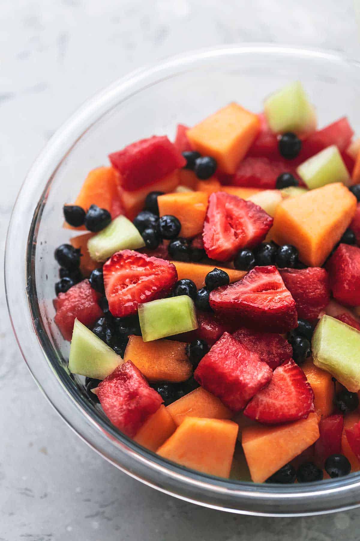 chopped melon chunks and fresh berries in a glass bowl