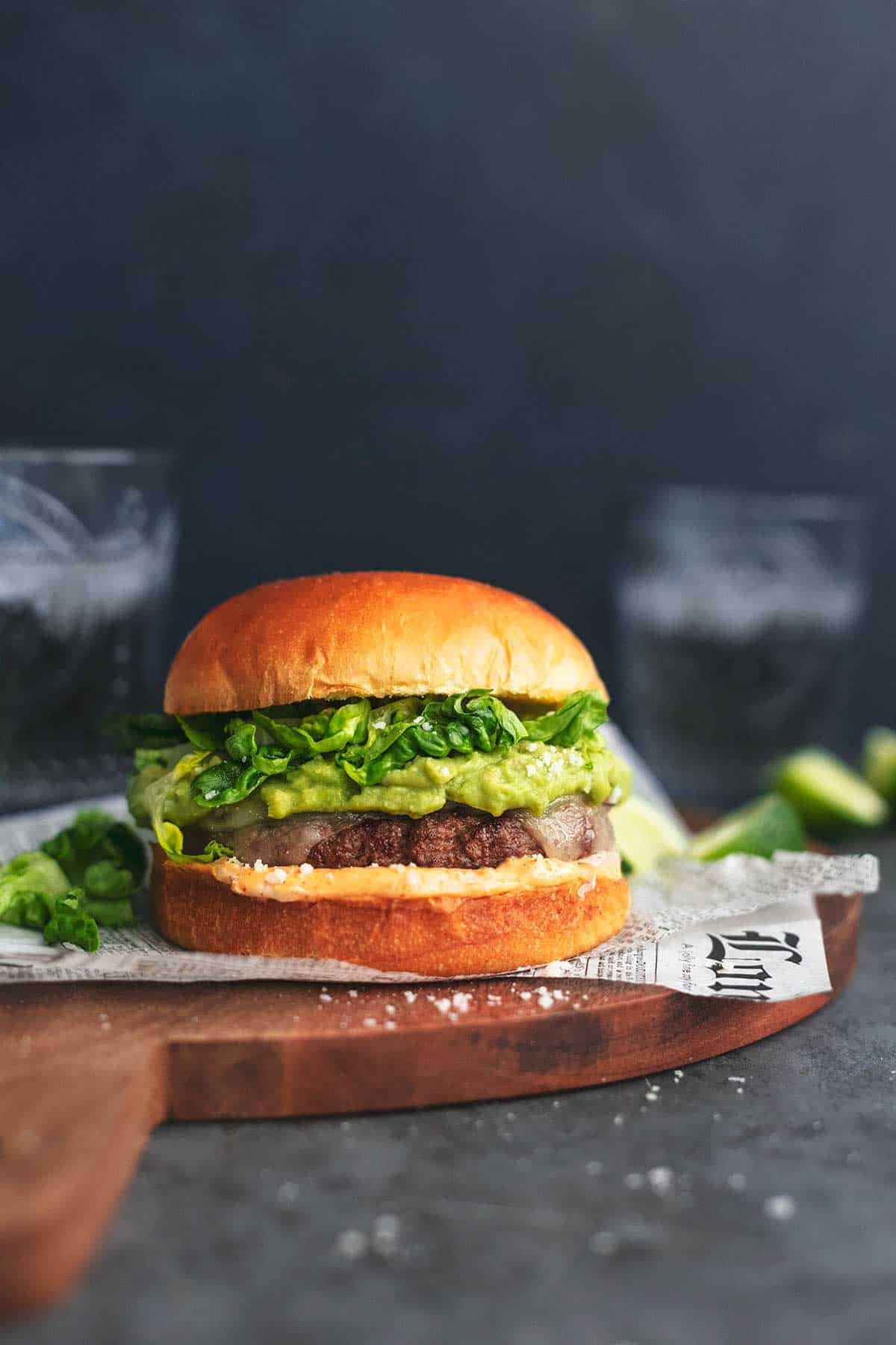 a tex-mex turkey burger on a cutting board with a glass of soda on the side.