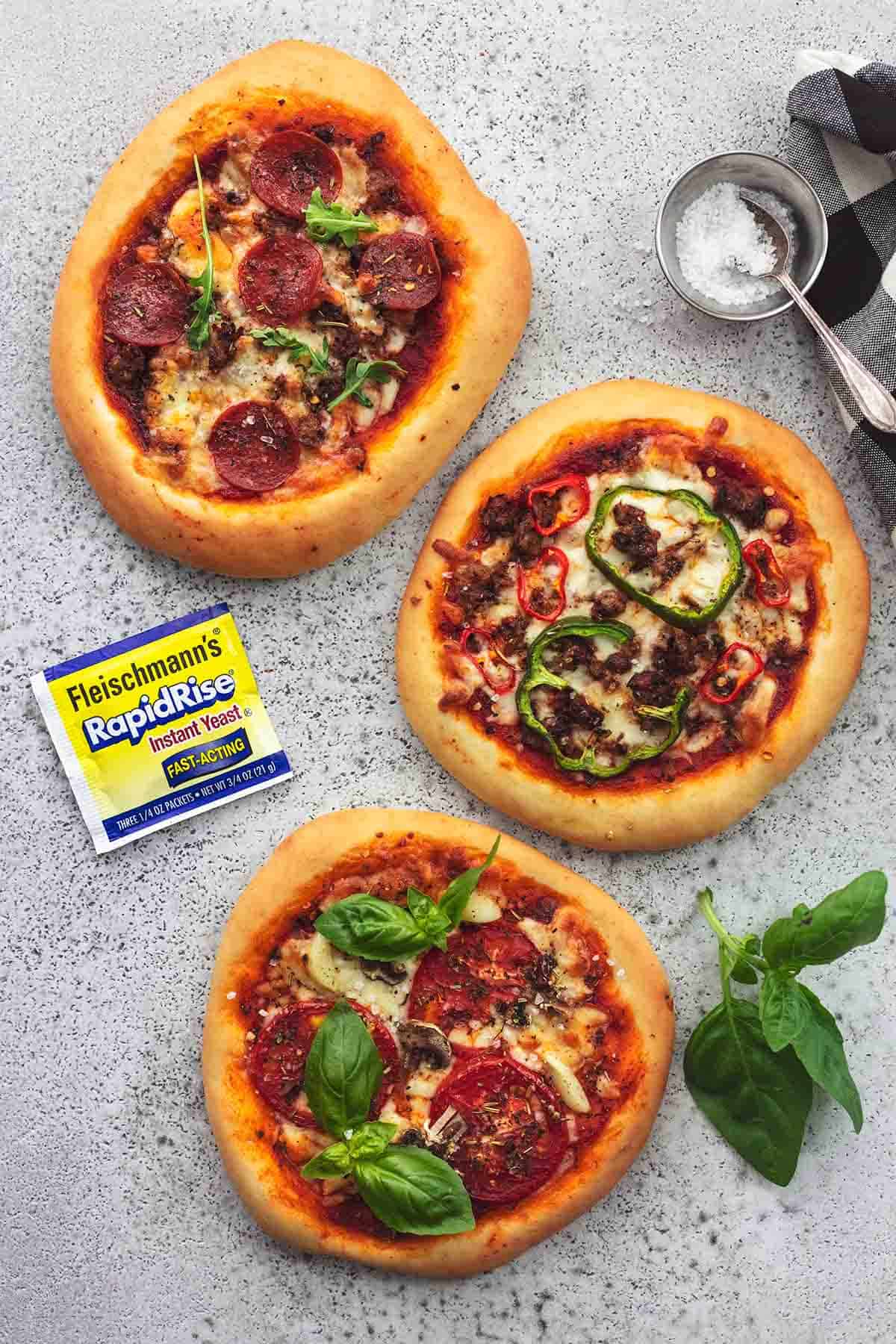 top view of personal pizzas with a yeast packet on the side.