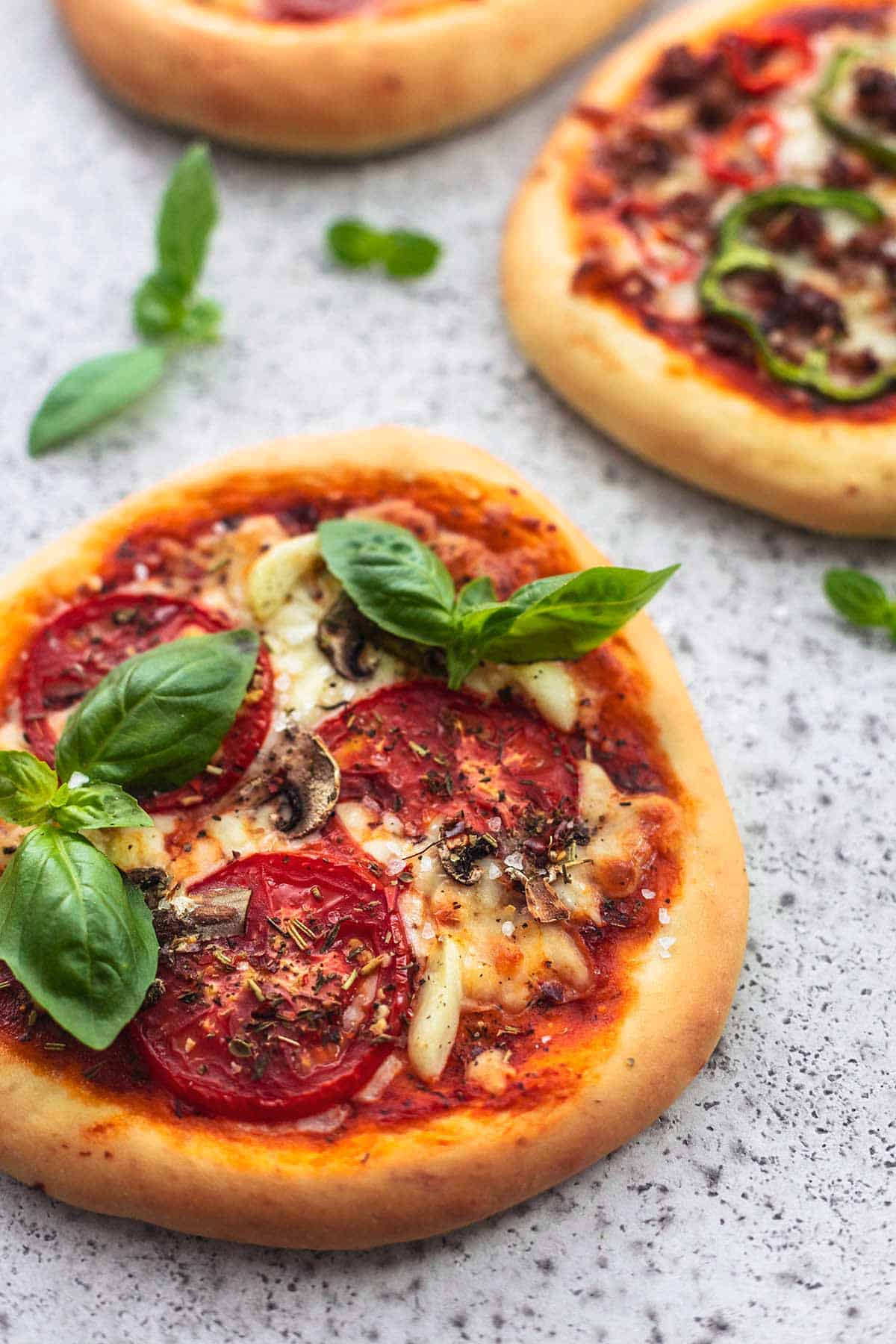 close up of a personal pizza with more personal pizzas in the background.