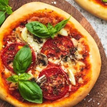 overhead view of small margherita pizza on wood cutting board