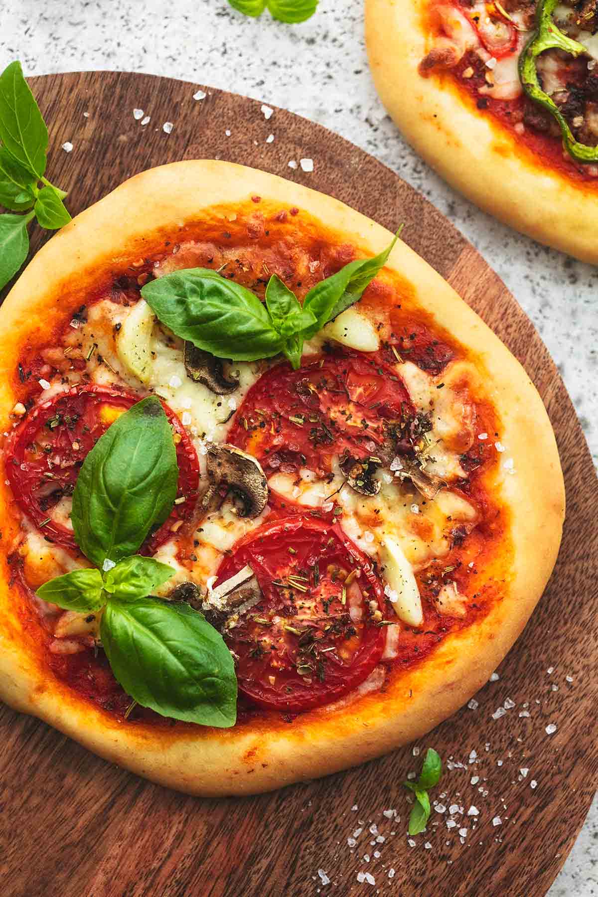 top view of a personal pizza on a wooden cutting board.