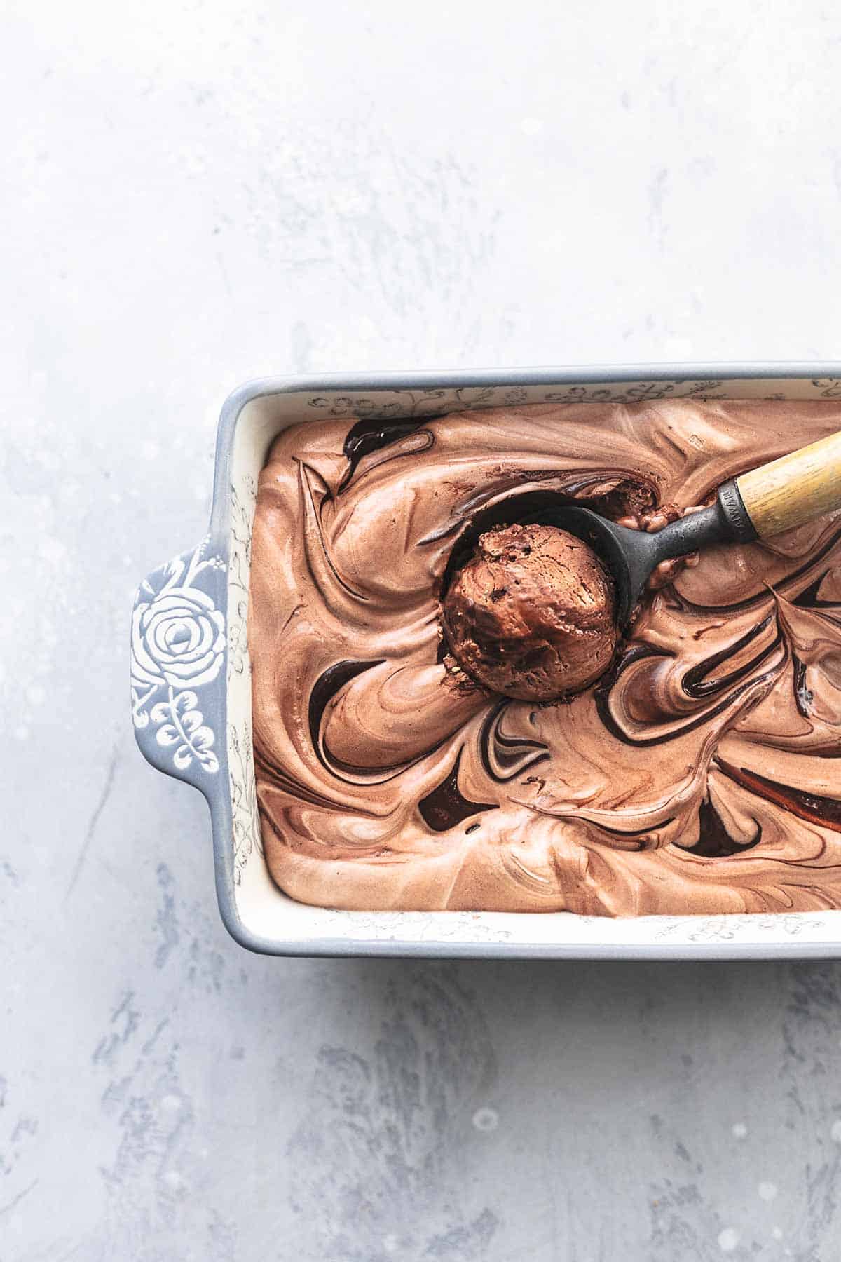 close up top view of fudge ripple chocolate ice cream with an ice cream scooper.