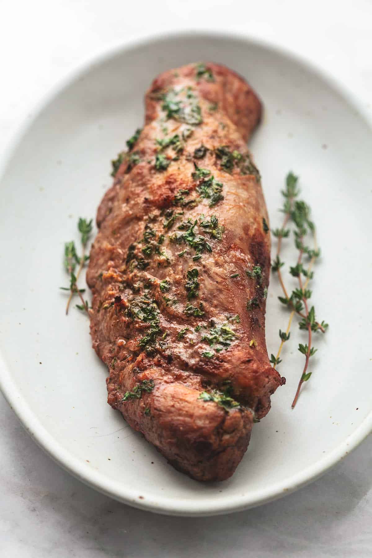 close up view of roasted pork tenderloin with herbs on top