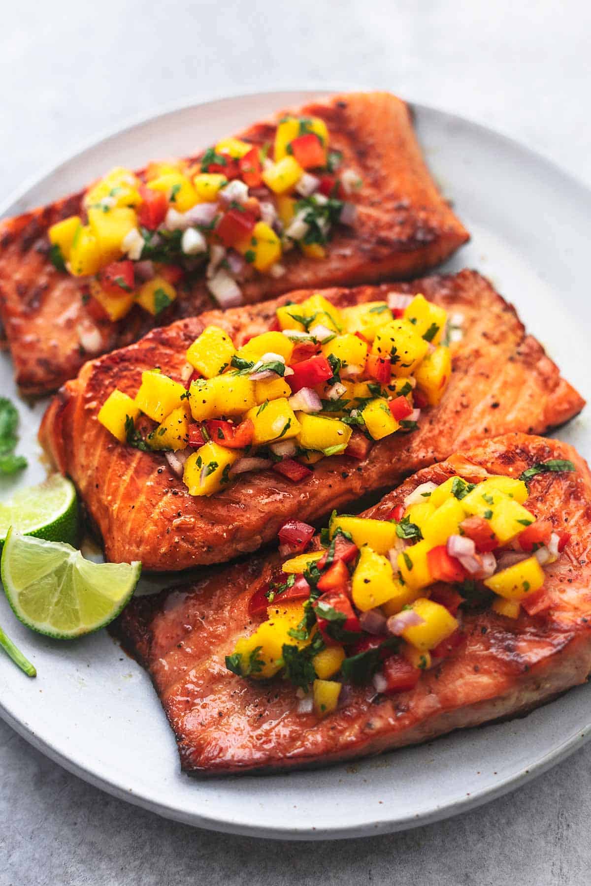 three pieces of salmon on a plate topped with mango salsa