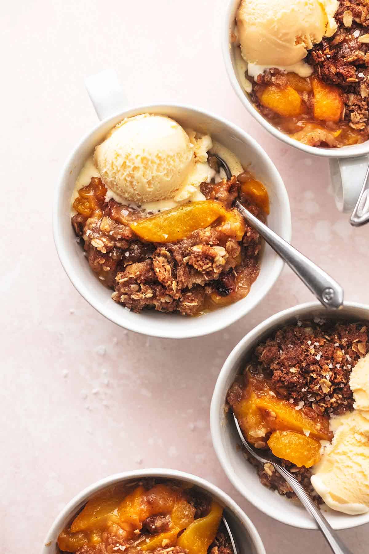 top view of peach crisp topped with vanilla ice cream in bowls.