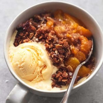 one bowl of peach crisp with scoop of ice cream and a spoon