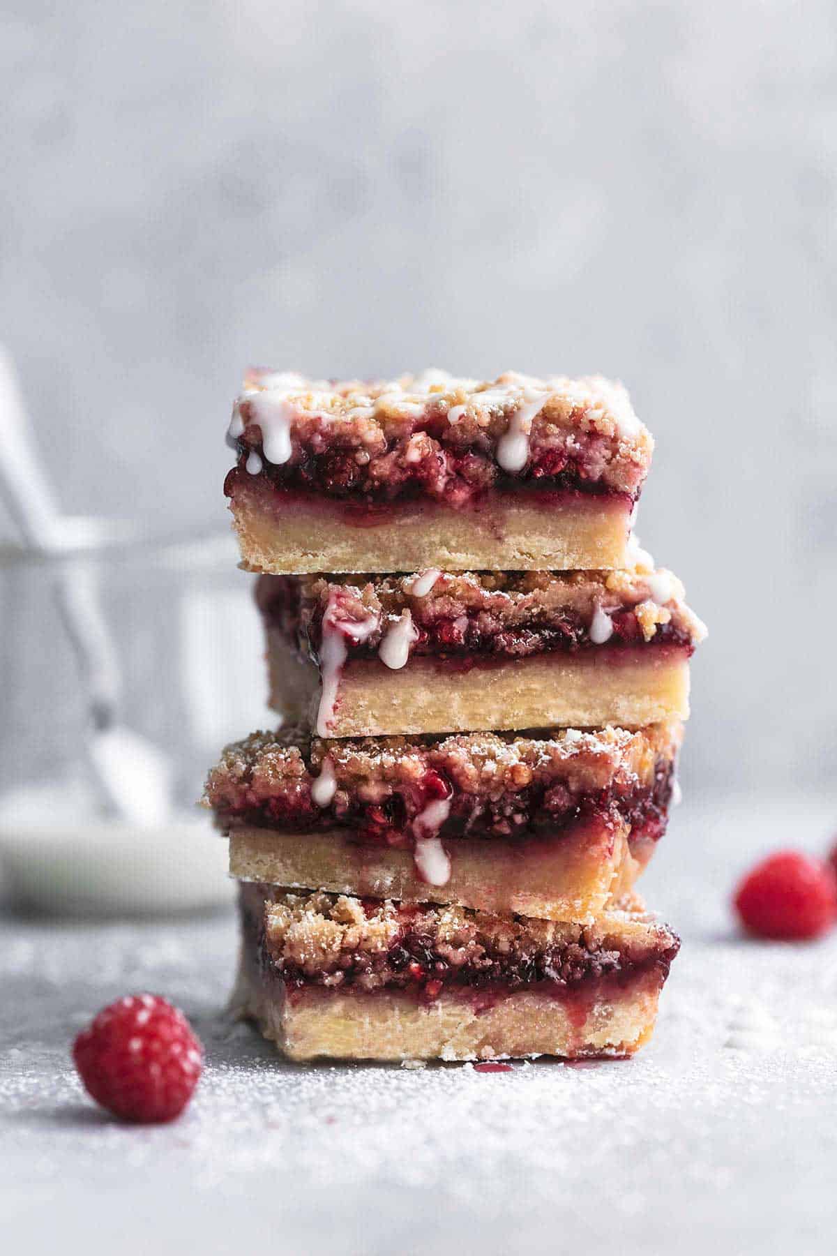 a stack of raspberry crumb bars with vanilla glaze.