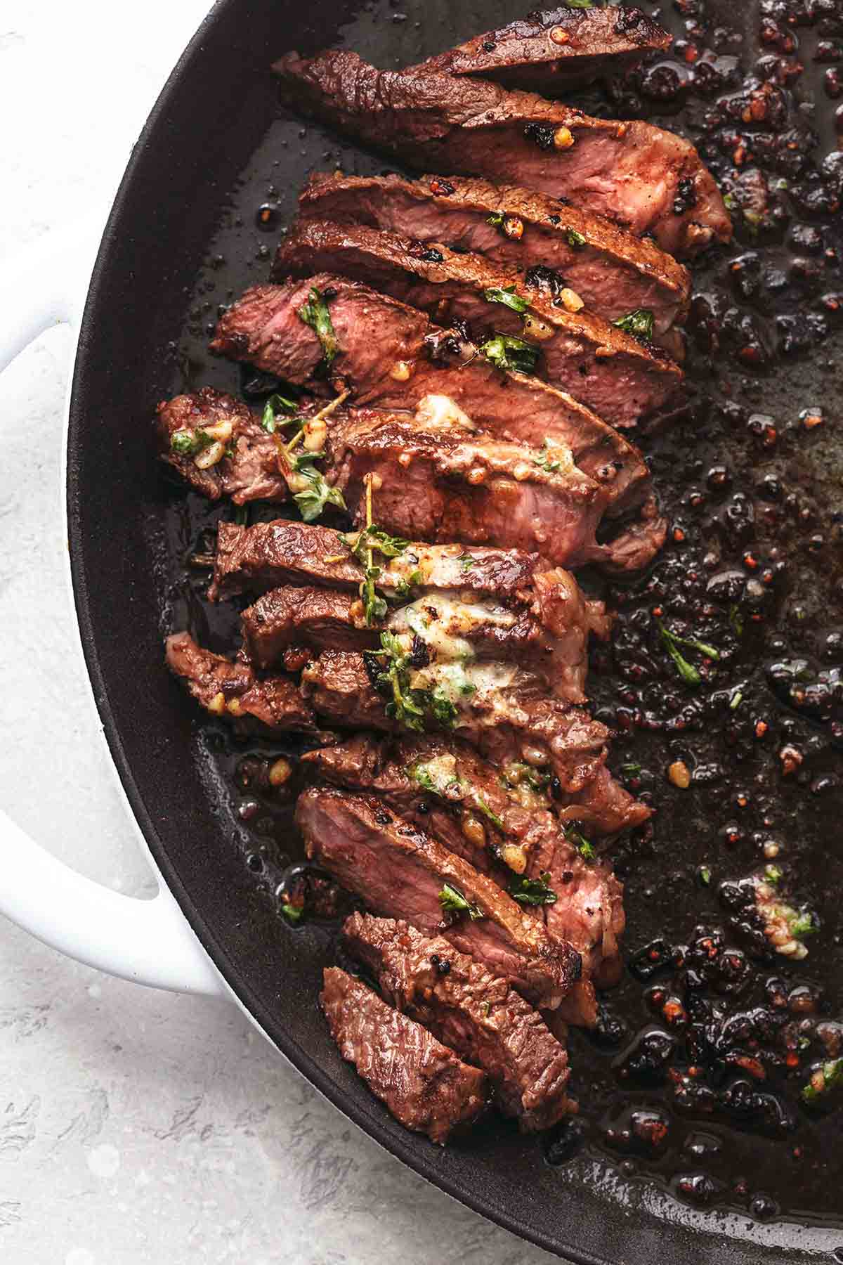 close up top view of sliced sirloin steak topped with herb butter.