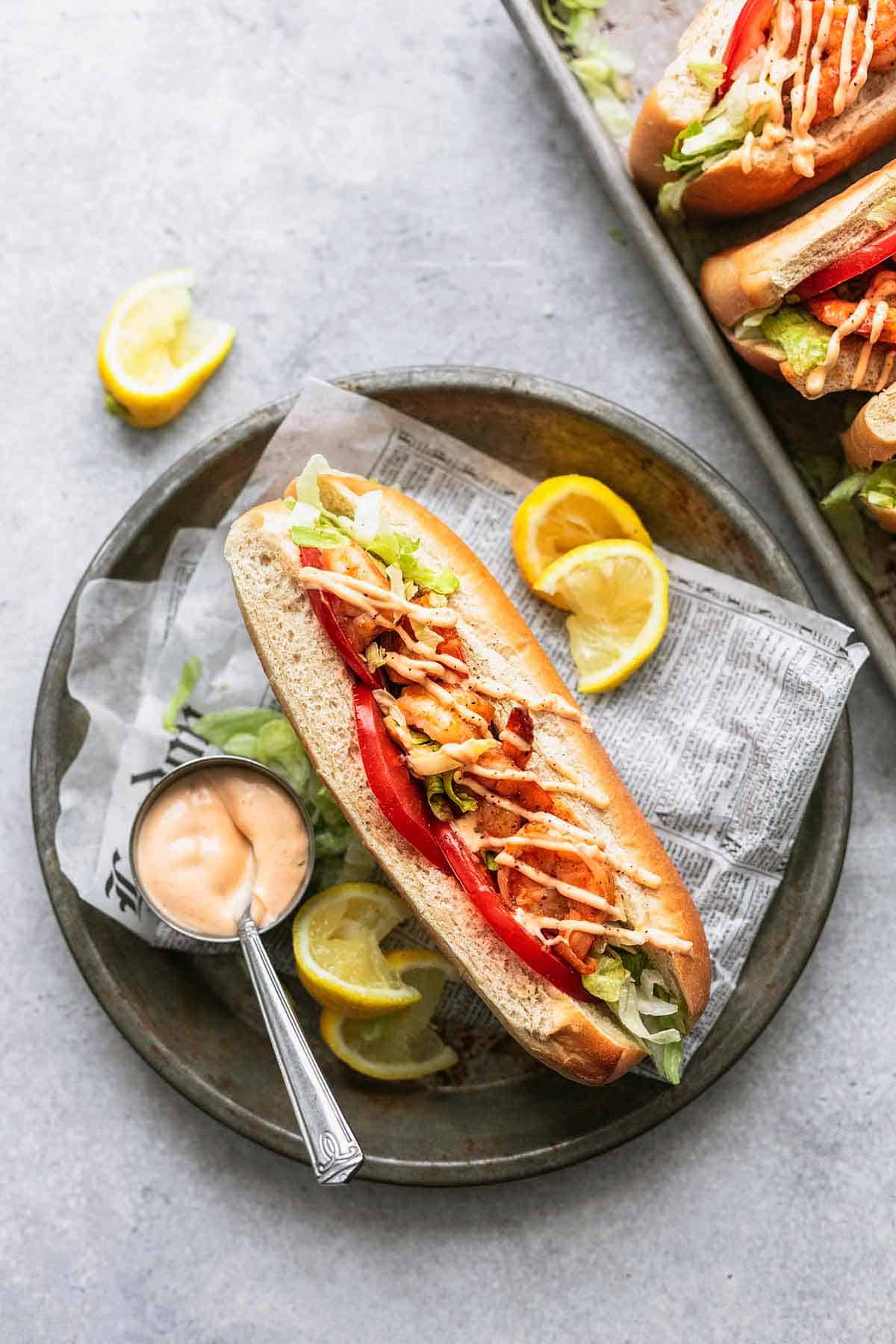 top view of a blackened shrimp po boy with sauce on the side on a platter.