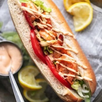 overhead close up view of split bun sandwich with tomatoes lettuce and shrimp