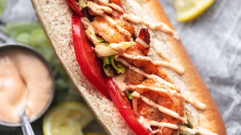 overhead close up view of split bun sandwich with tomatoes lettuce and shrimp