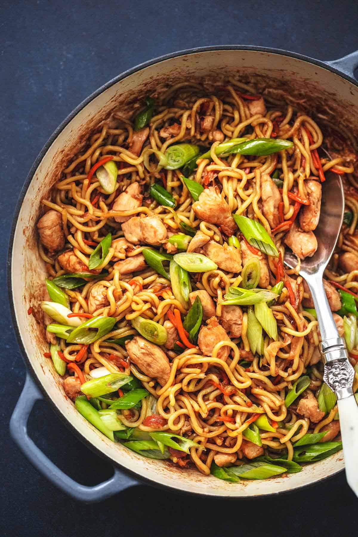 top view of chicken chow mein in a skillet with a serving spoon.