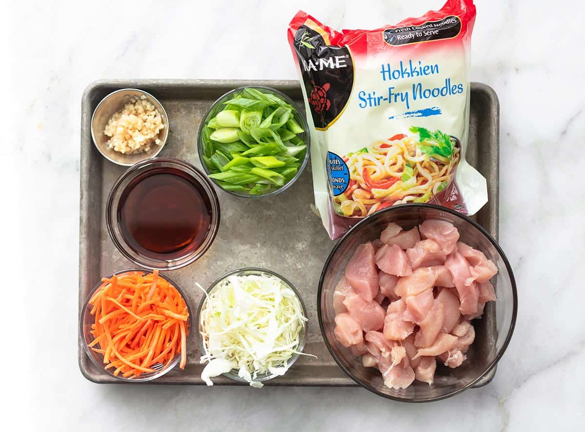 top view of ingredients for chicken chow mein on a baking sheet.