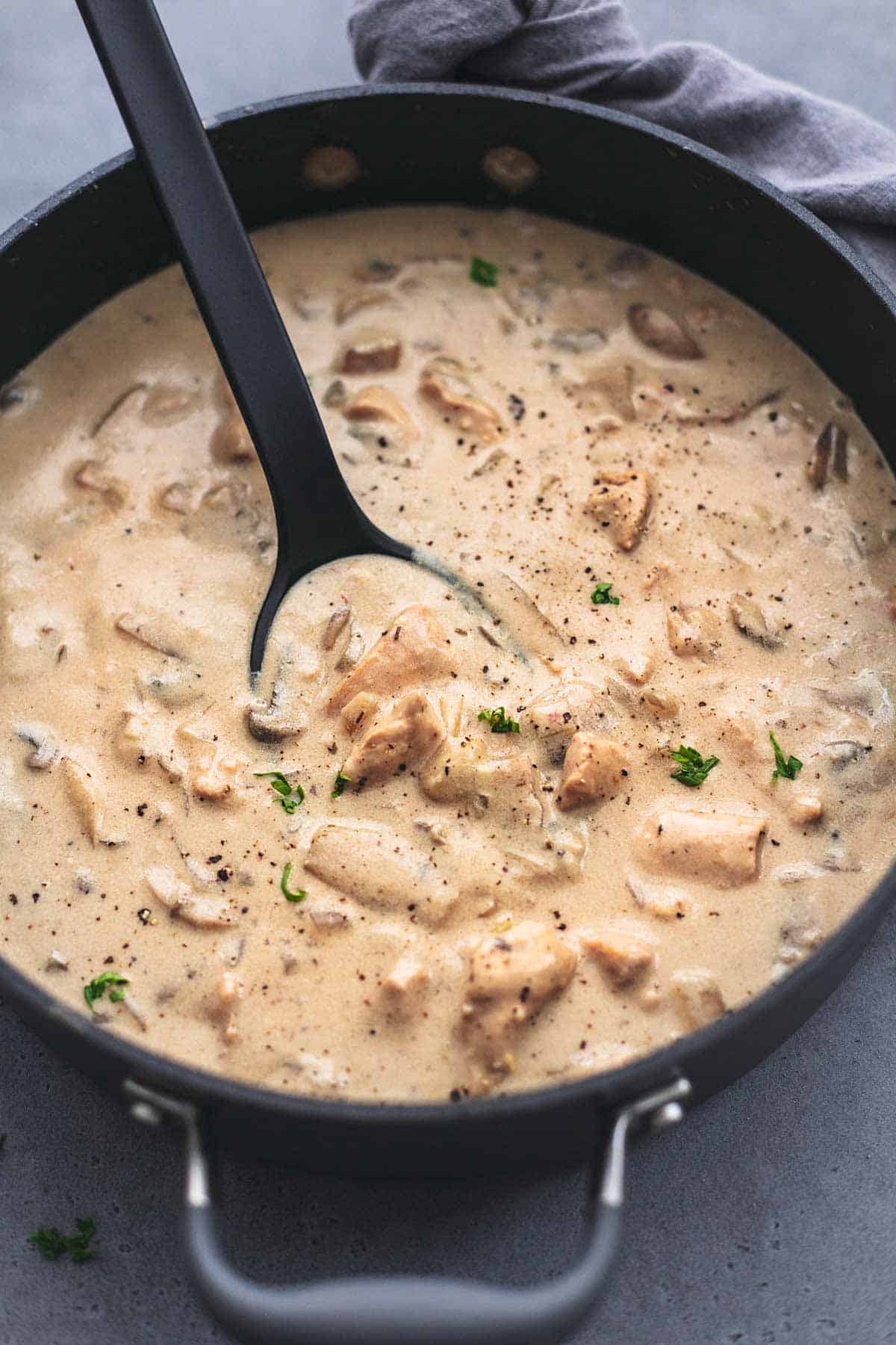 close up of chicken stroganoff in a skillet with a serving spoon.