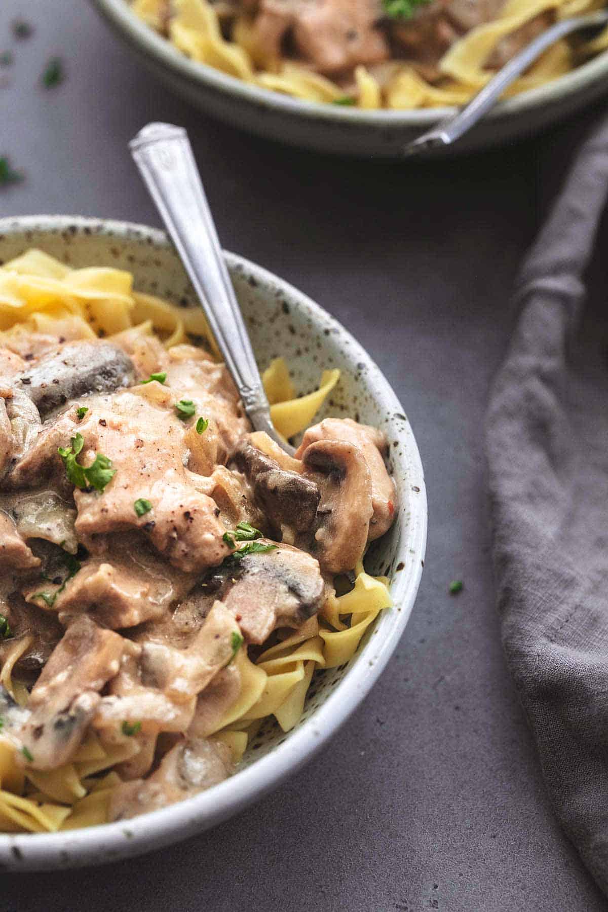 1/4 view of bowl filled with chicken and mushroom in brown sauce over noodles in 