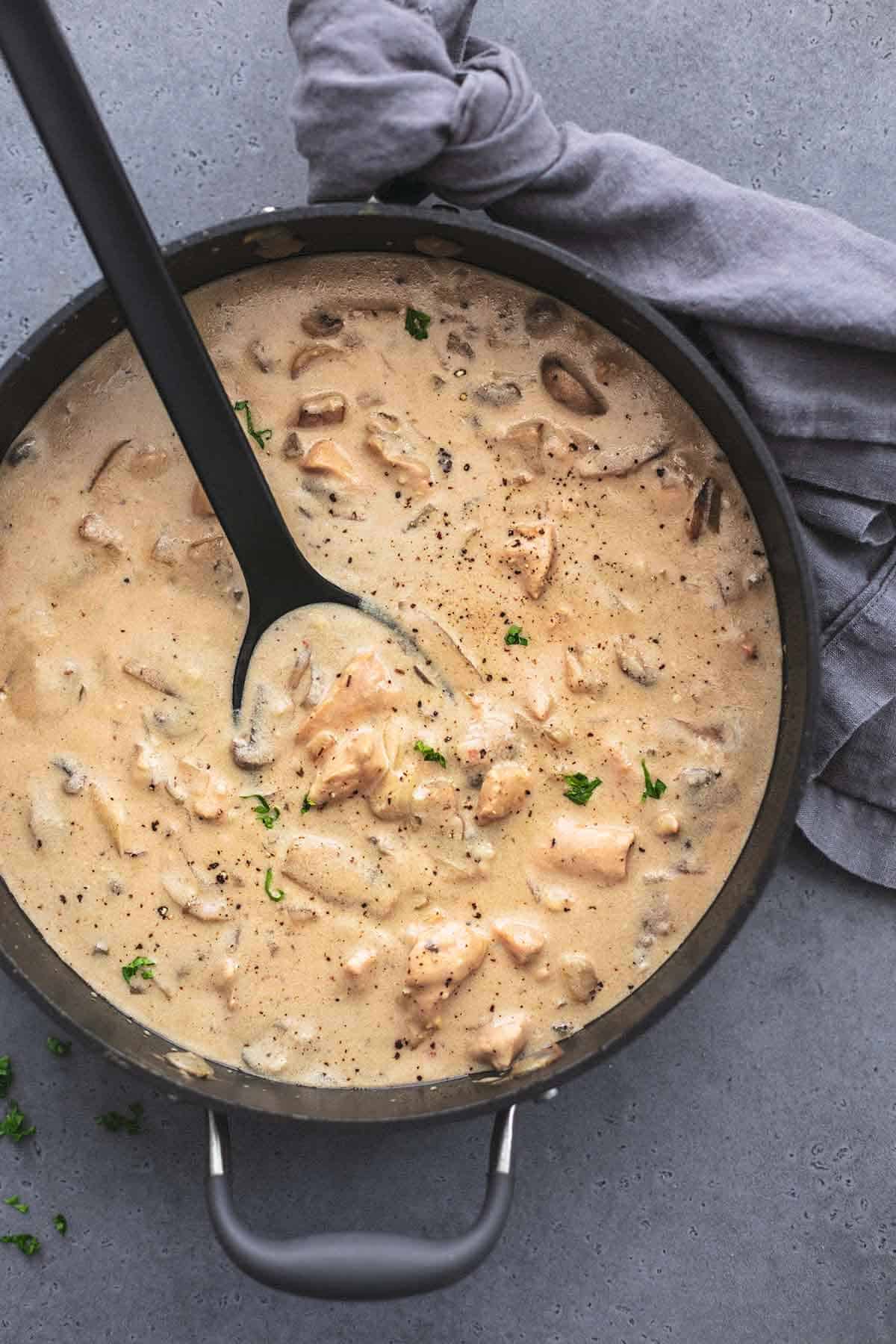 top view of chicken stroganoff with a serving spoon in a skillet.