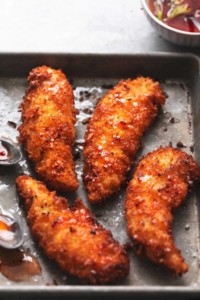 up close view of four pieces of breaded chicken with sea salt on metal pan